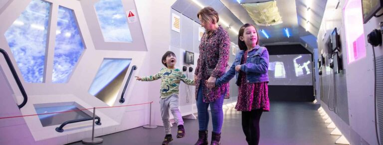 Grandmother with young children inside Life Science Centre's Internation Space Station mock-up.