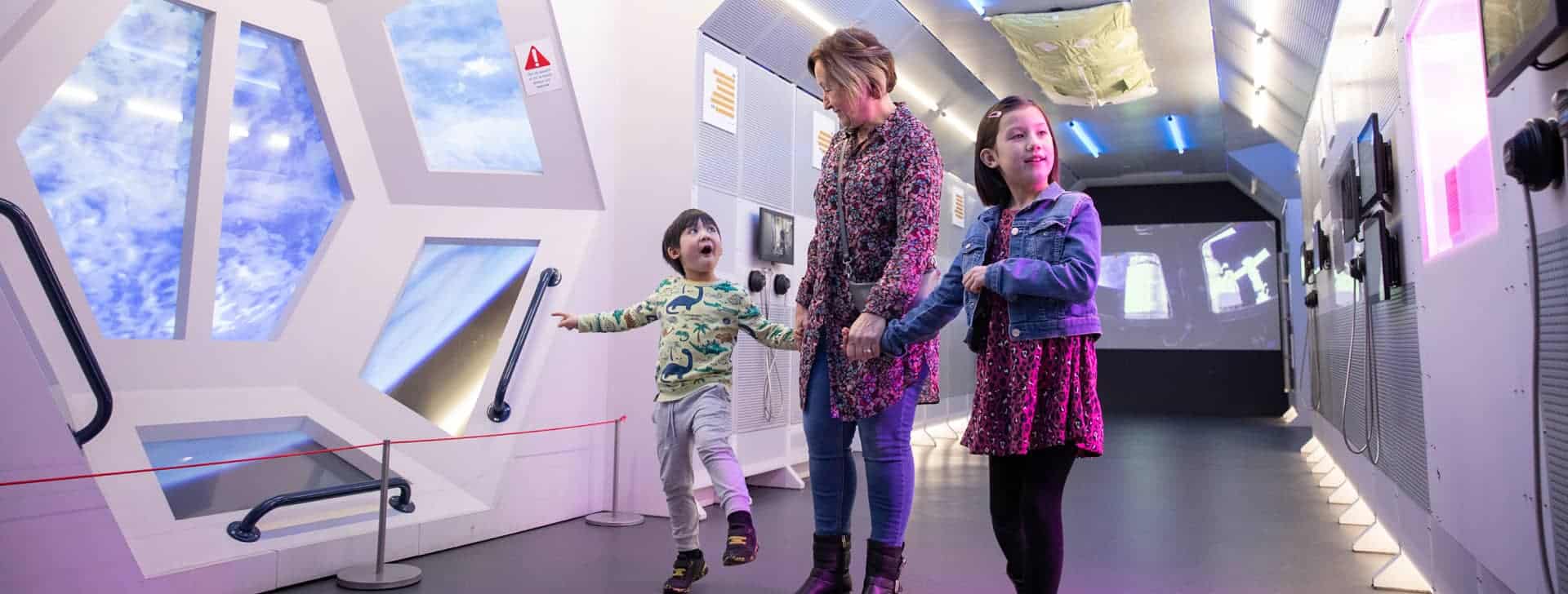 Grandmother with young children inside Life Science Centre's Internation Space Station mock-up.