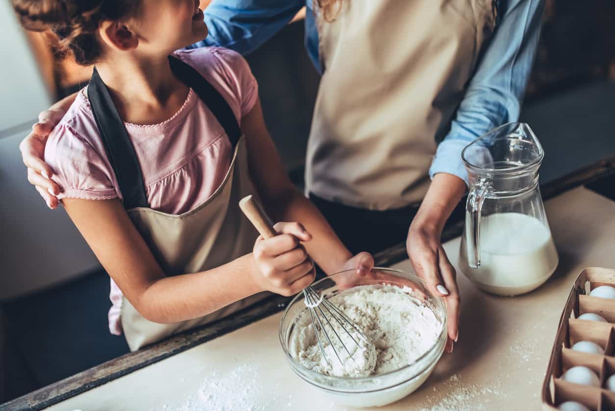 Mum with daughter in kitchen making home-made ice cream.