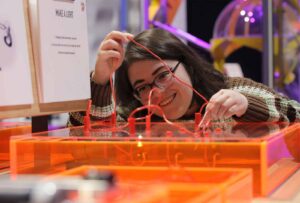 Adult female experimenting with wires and electricity in Life's Wow Zone.