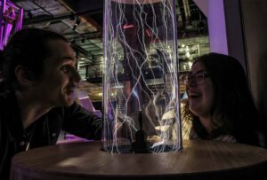 Adults experimenting with lightning bolts in a glass tube in Wow Zone.