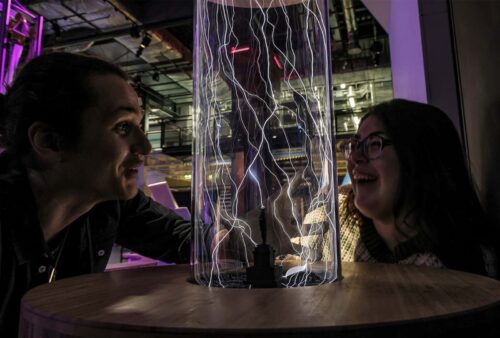 Adults experimenting with lightning bolts in a glass tube in Wow Zone.
