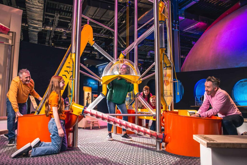 Family Playing in Life science centre Wow Zone, having hands on fun with the big machine.