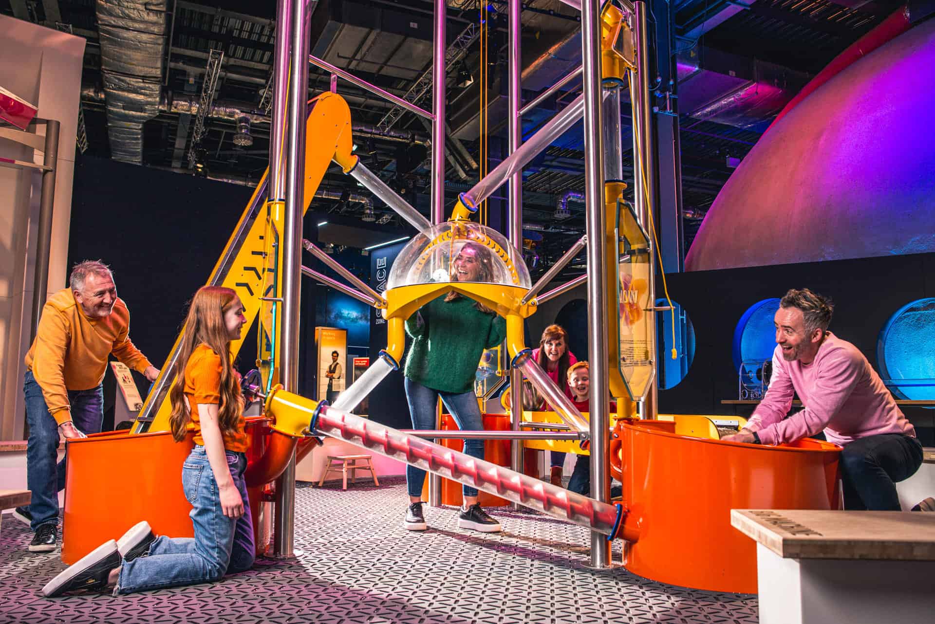 Family Playing in Life science centre Wow Zone, having hands on fun with the big machine.