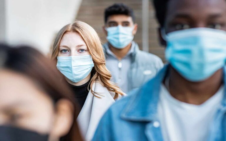 Authentic shot of multiracial people in the city wearing face mask and walking on the pavement commuting to work