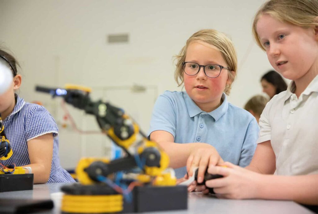 School children operating a robotic device in science workshop.