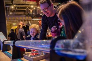 Family enjoying a hands-on activity experimenting with speed in Life Science Centre's Wow Zone.