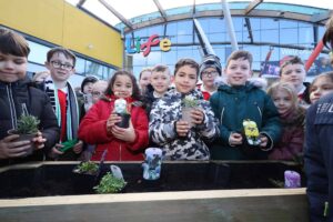School Children Holding Bee Friendly Planters In Front Of Life Science Centre.