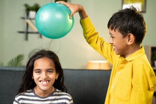 Focus On Boy, Kids Enjoys Static Cling Experiment By Playing While Rubbing Ballon To Hair And Hairs Attracted To Ballon Conept Of Excitement And Home Science Experiment.