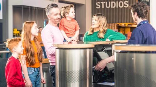 Family of five at reception area purchasing tickets to visit Life Science Centre.