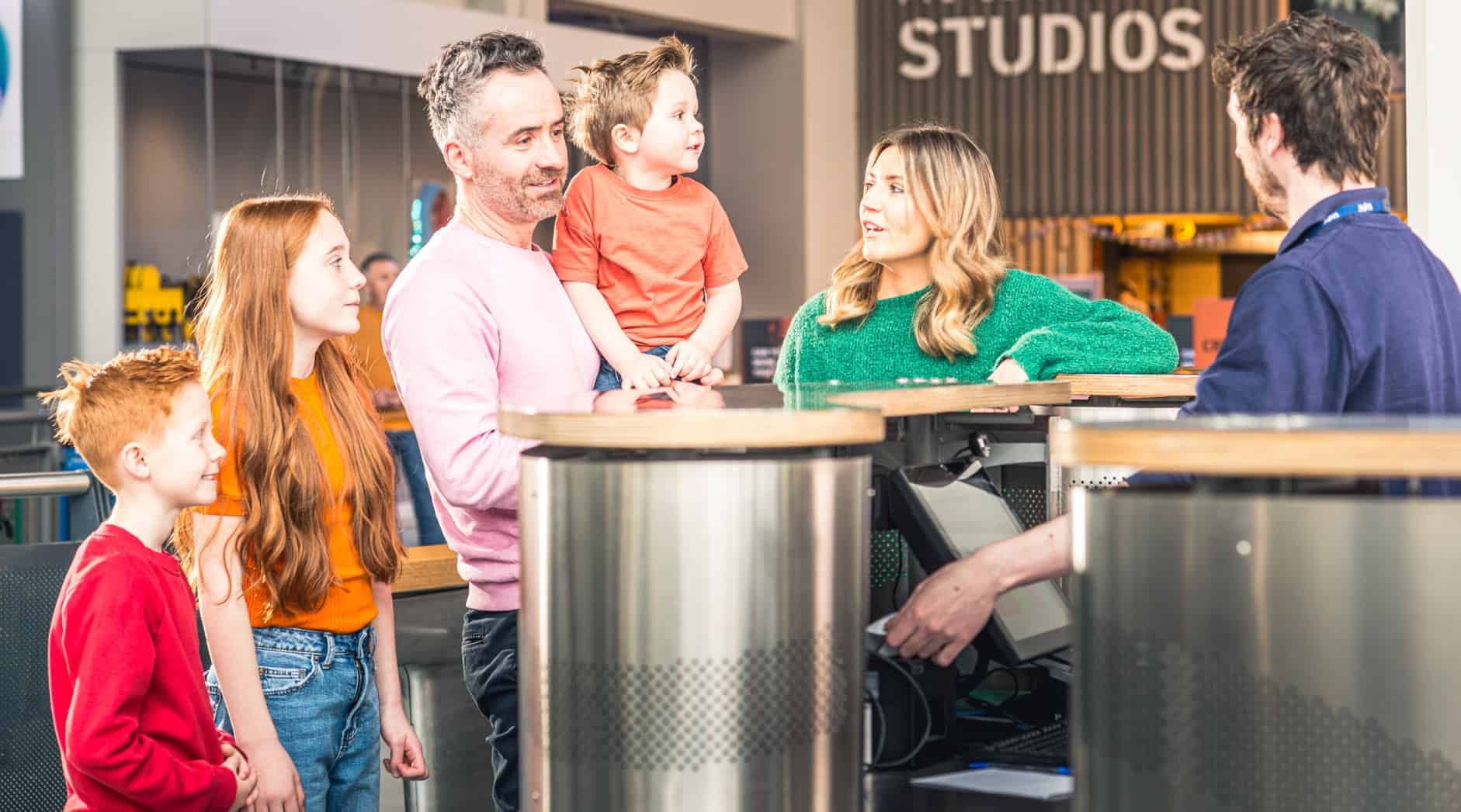 Family of five at reception area purchasing tickets to visit Life Science Centre.