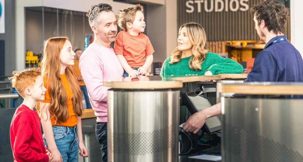Family of five at reception area purchasing tickets to visit Life Science Centre.