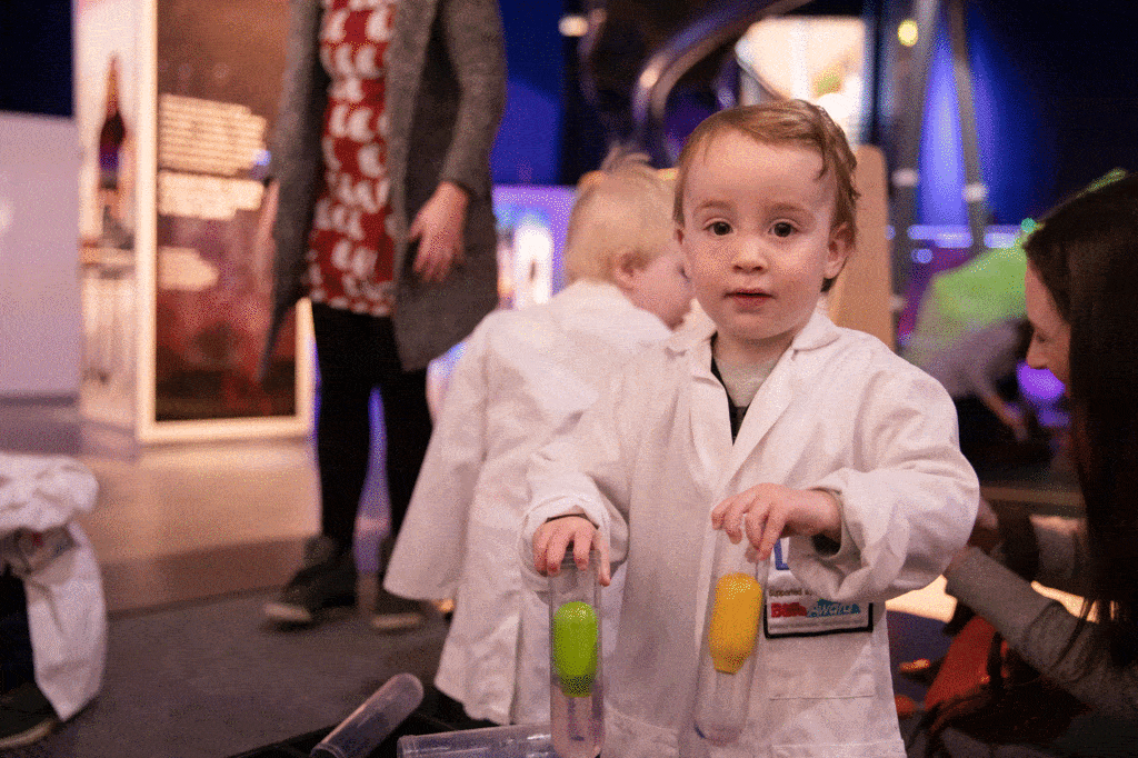 Toddler in a white lab coat at Life Science Centre.