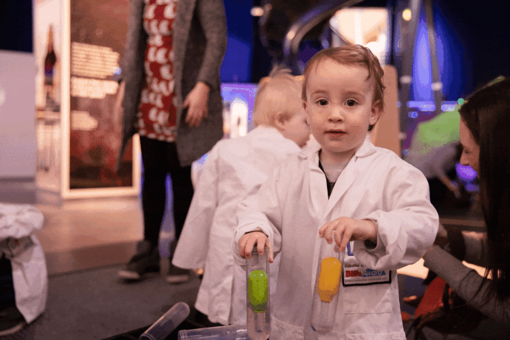 Toddler in a white lab coat at Life Science Centre.