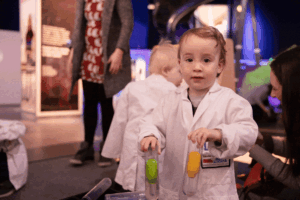 Toddler in a white lab coat at Life Science Centre.