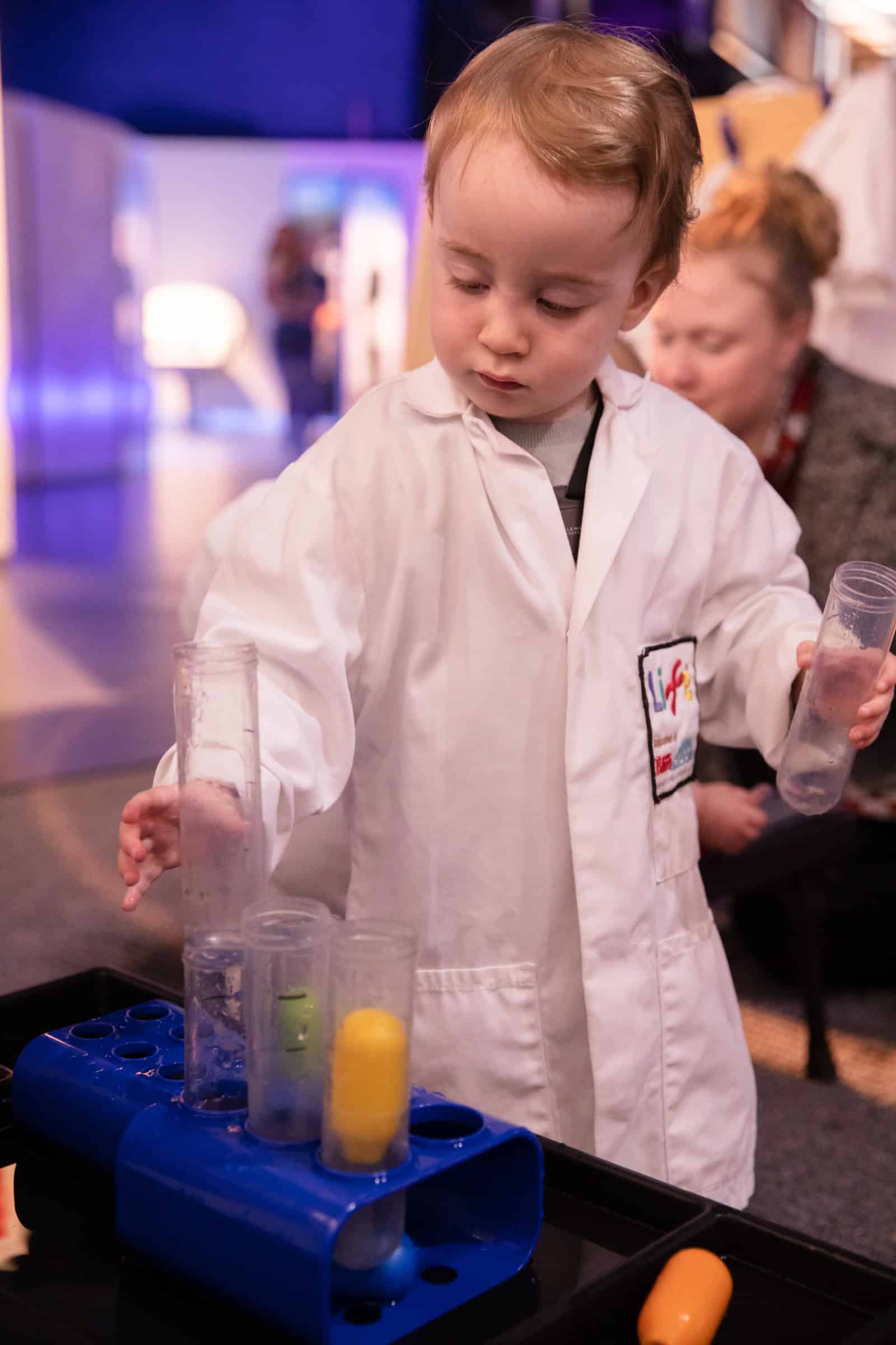 Toddler in a white lab coat at Life Science Centre.