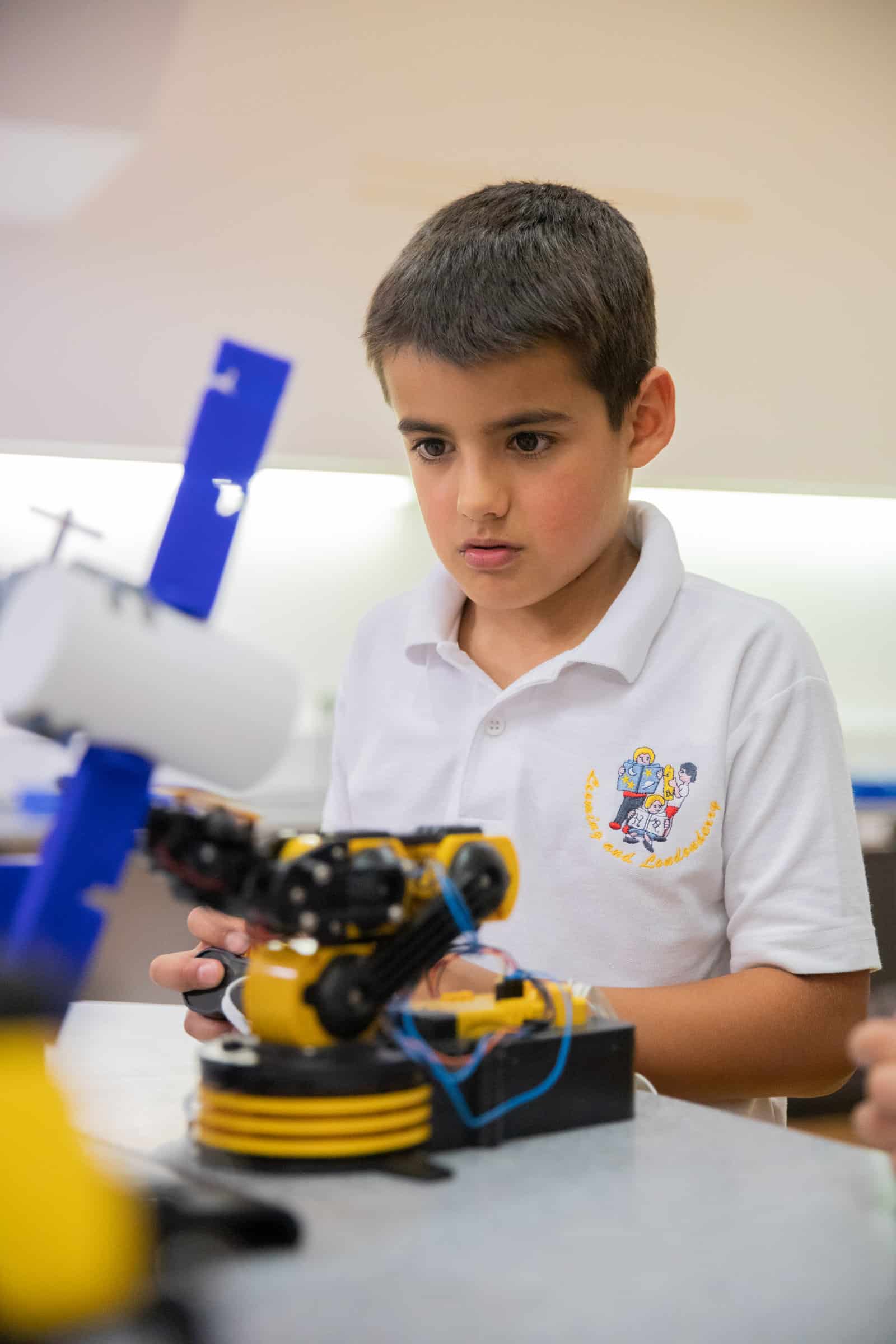 School child operating robot arm with controller.