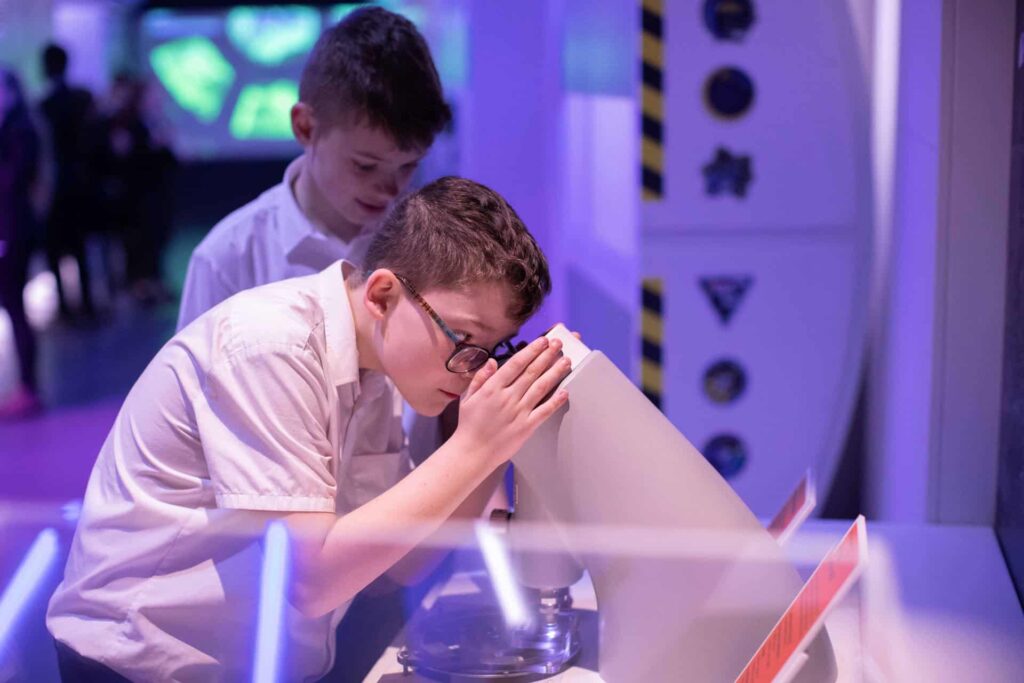 School child looking down a microscope.