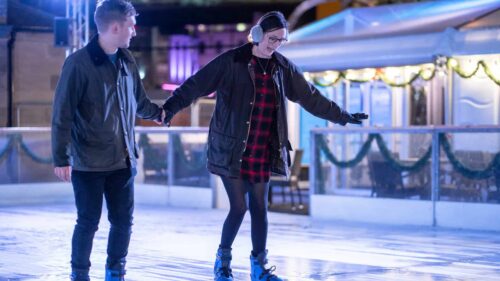 Couple holding hands whilst skating on Newcastle's open-air ice rink.