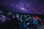 Family of all ages in Life science centre's planetarium watching a 'Just Look Up'.