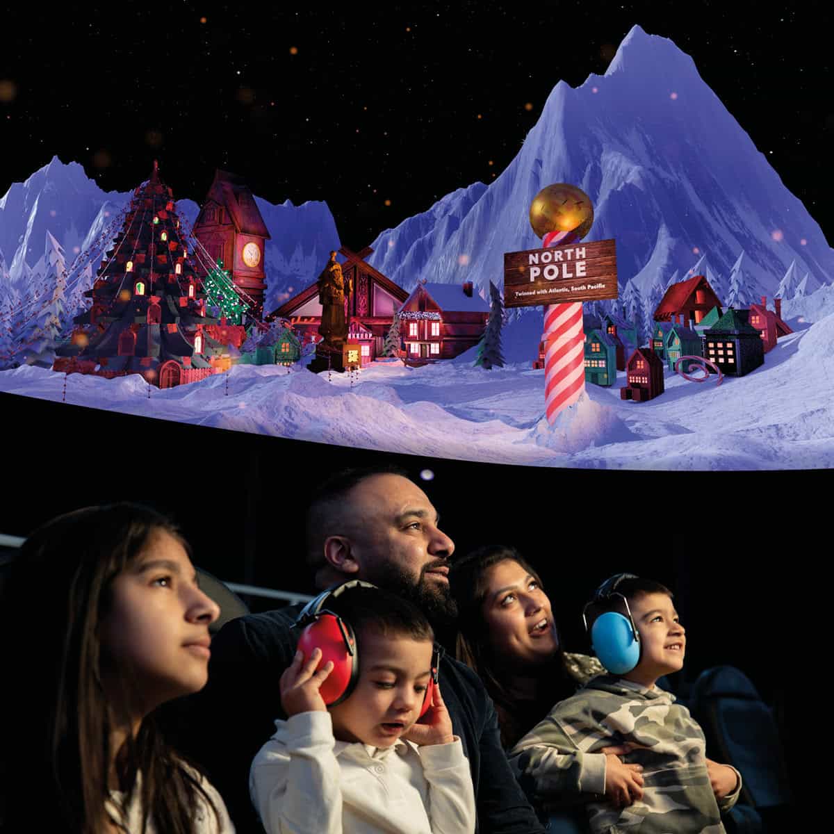 Family in planetarium watching What Santa Sees show and wearing ear defenders.