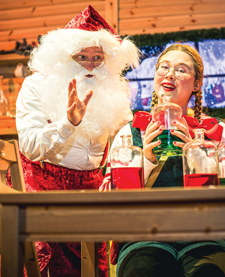 Santa with elf doing festive science demo with brightly coloured liquid in bottle at Newcastle's Life Science Centre.