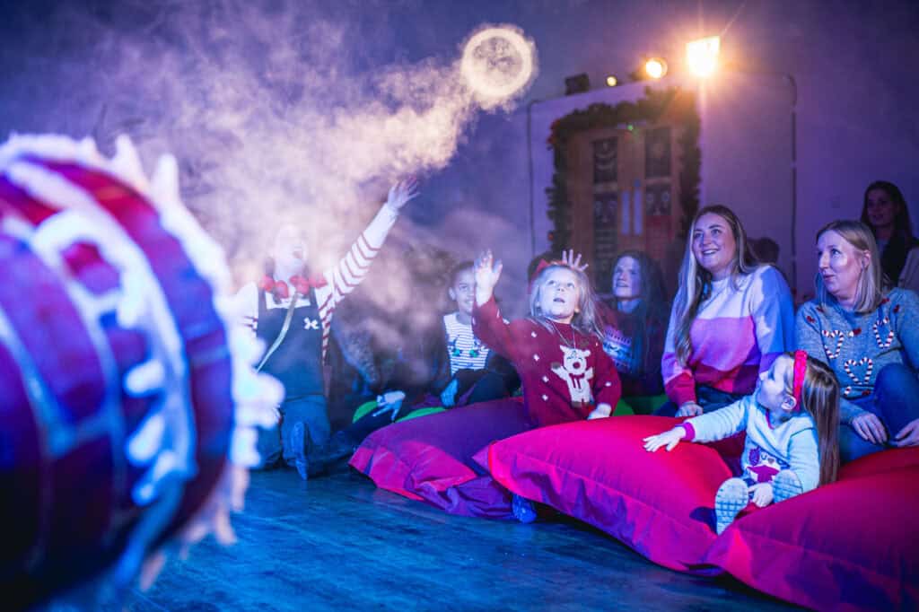 Santa and elf with children receiving a Christmas gift in his Grotto at Newcastle's Life Science Centre.