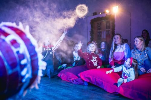 Santa and elf with children receiving a Christmas gift in his Grotto at Newcastle's Life Science Centre.