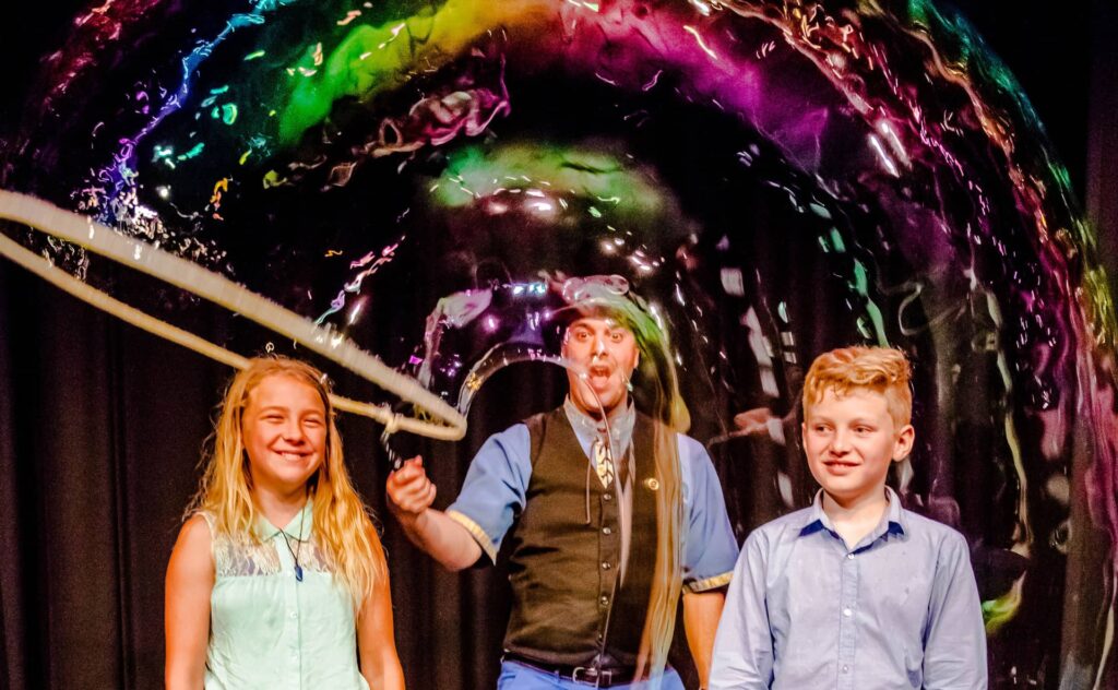 The Highland Joker doing a bubble demonstration with children on stage.