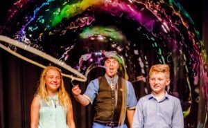 The Highland Joker doing a bubble demonstration with children on stage.