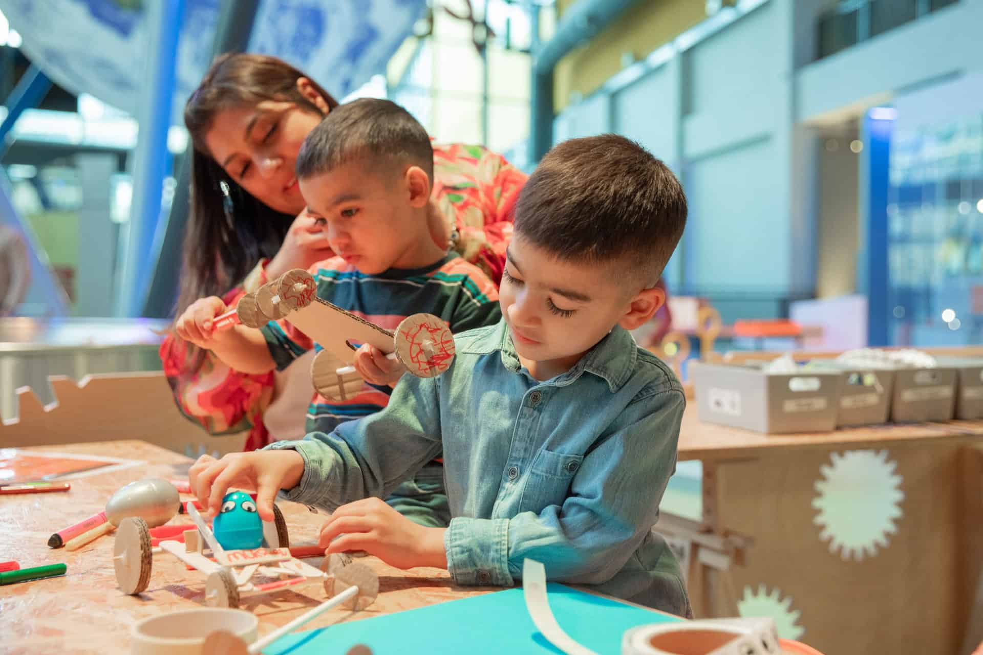 Mother with two boys in Life Science Centre's Making Studios creating an egg-mobile during the Easter holidays.