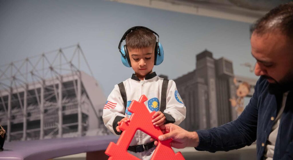 Child wearing ear defenders in Life Science Centre's Play Zone.
