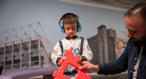 Child wearing ear defenders in Life Science Centre's Play Zone.