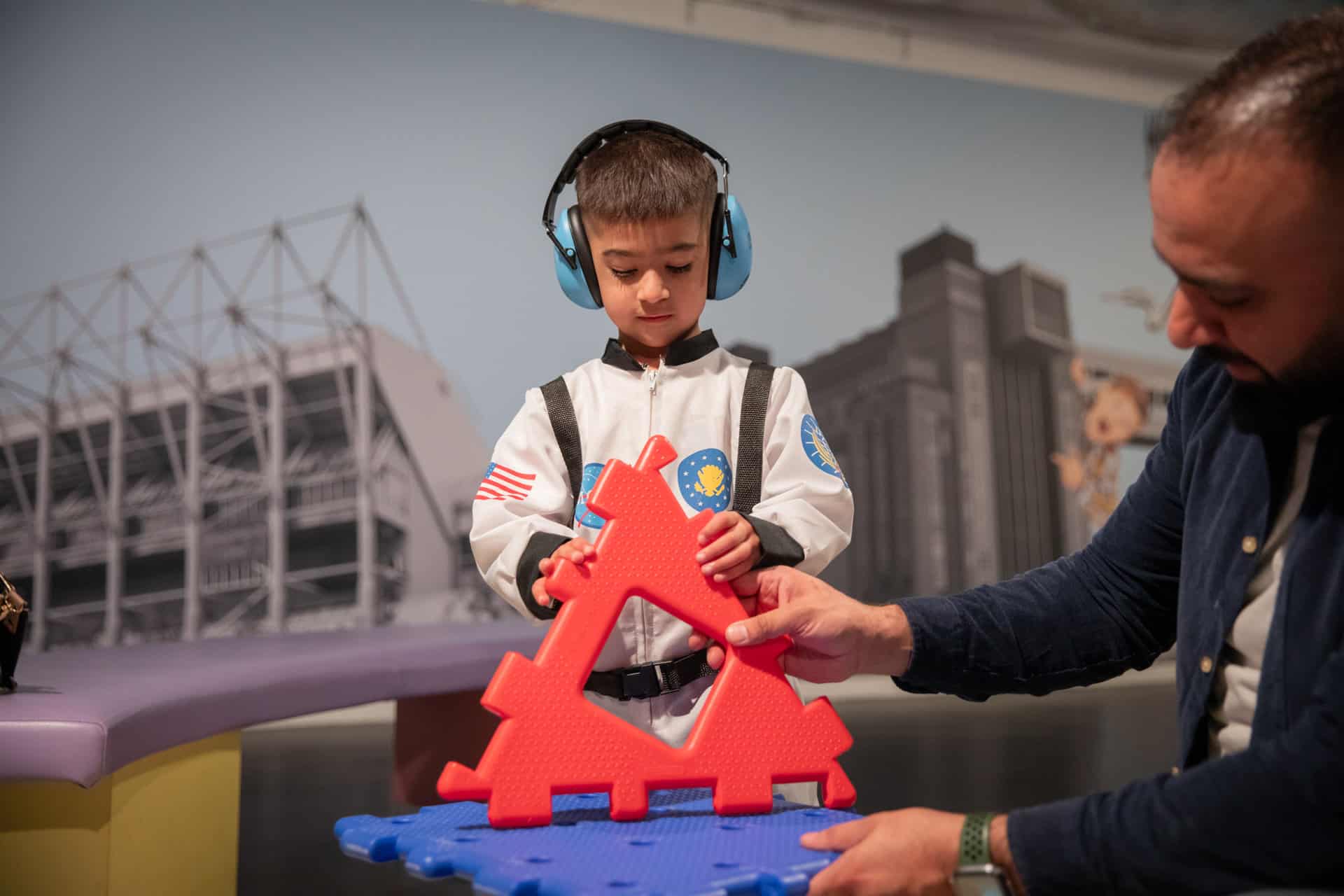 Child wearing ear defenders in Life Science Centre's Play Zone.