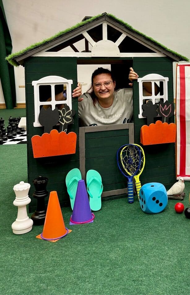 Two team members in wendyhouse with summer activities surrounding them such as beach balls and giant chess pieces.