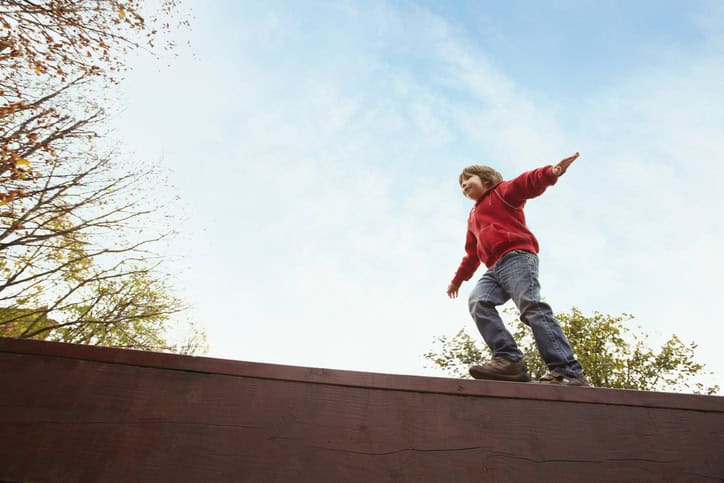 Boy Balancing On Wooden Wall