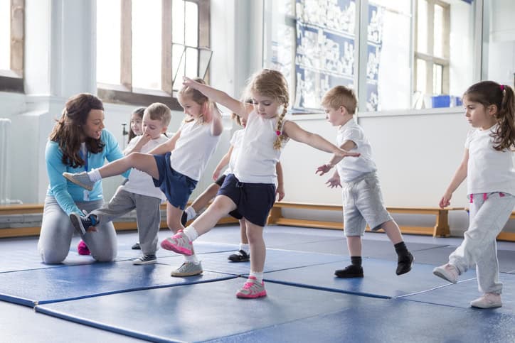 Nursery teacher helping one of her students during a physical education lesson.
