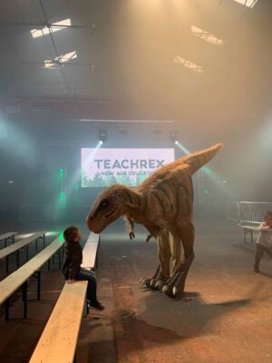 Huge dinosaur puppet looking down at child in science centre Halloween show.