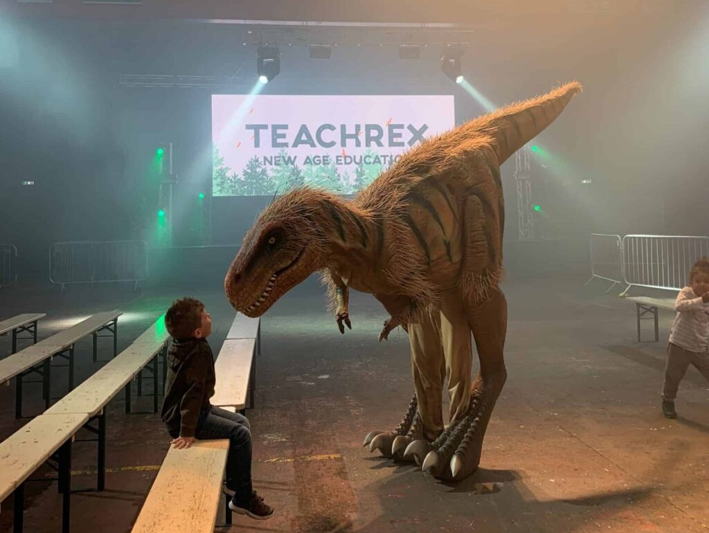 Huge dinosaur puppet looking down at child in science centre Halloween show.