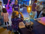 Little girl looking through a microscope as part of a science demo.
