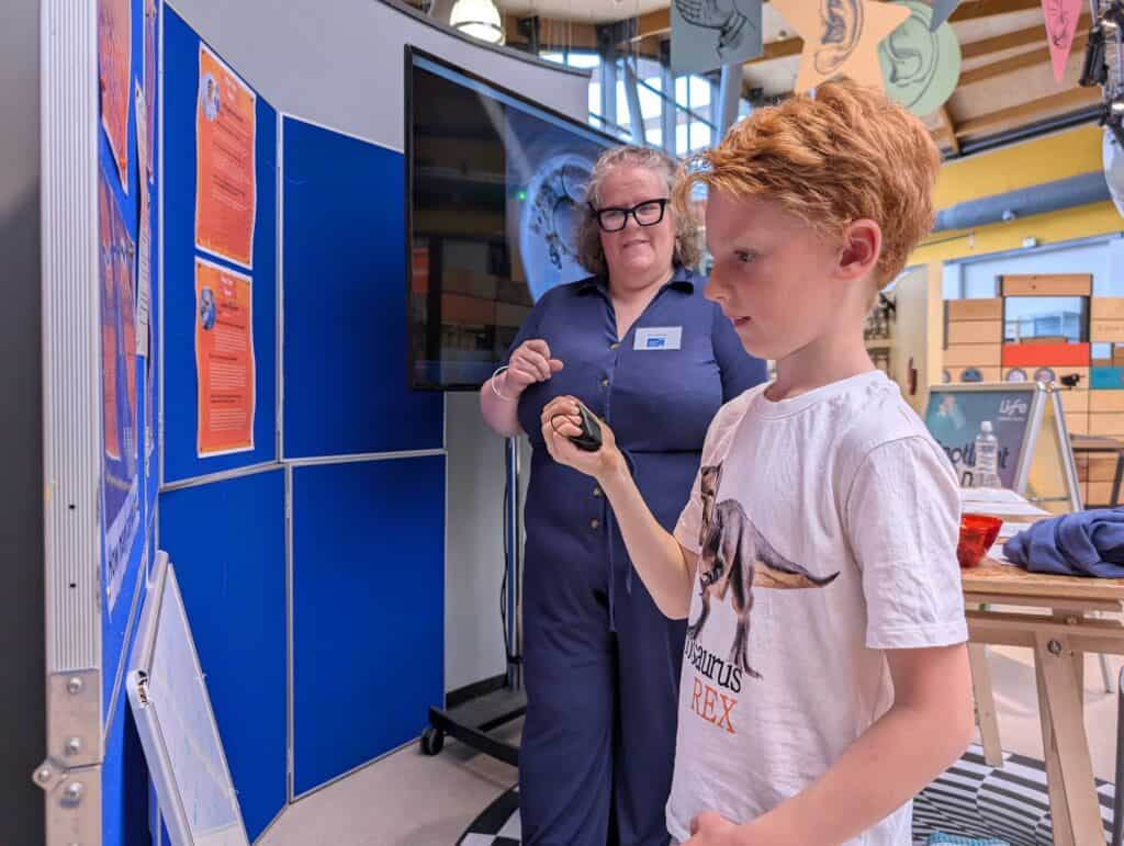 Little boy enjoying hands-on activity assisted by scientist.