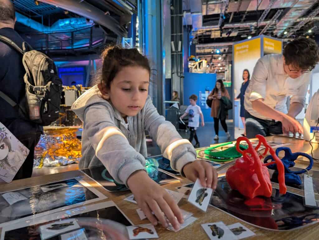 Young girl reaching for something at Spotlight on Space Day in Life Science Centre.