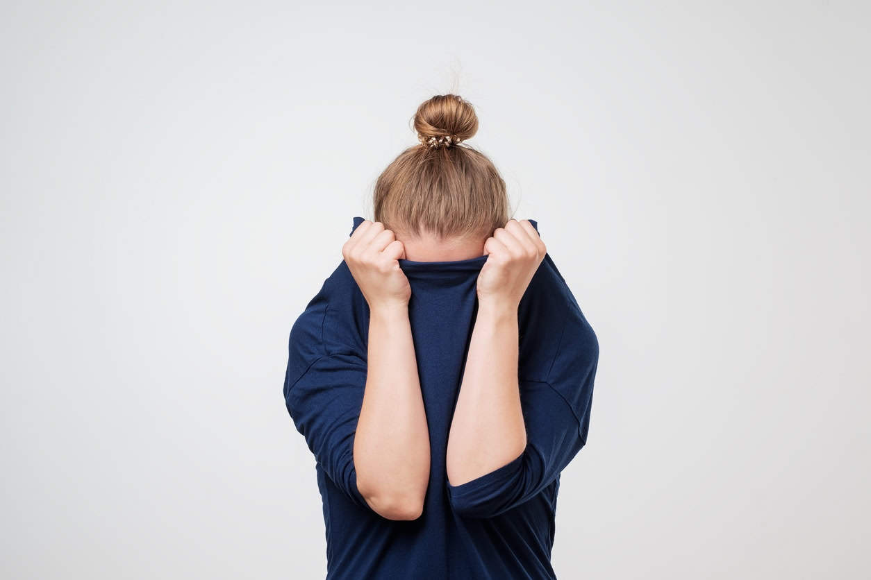 European Woman Hiding Face Under The Clothes. She Is Oulling Sweater On Her Head.