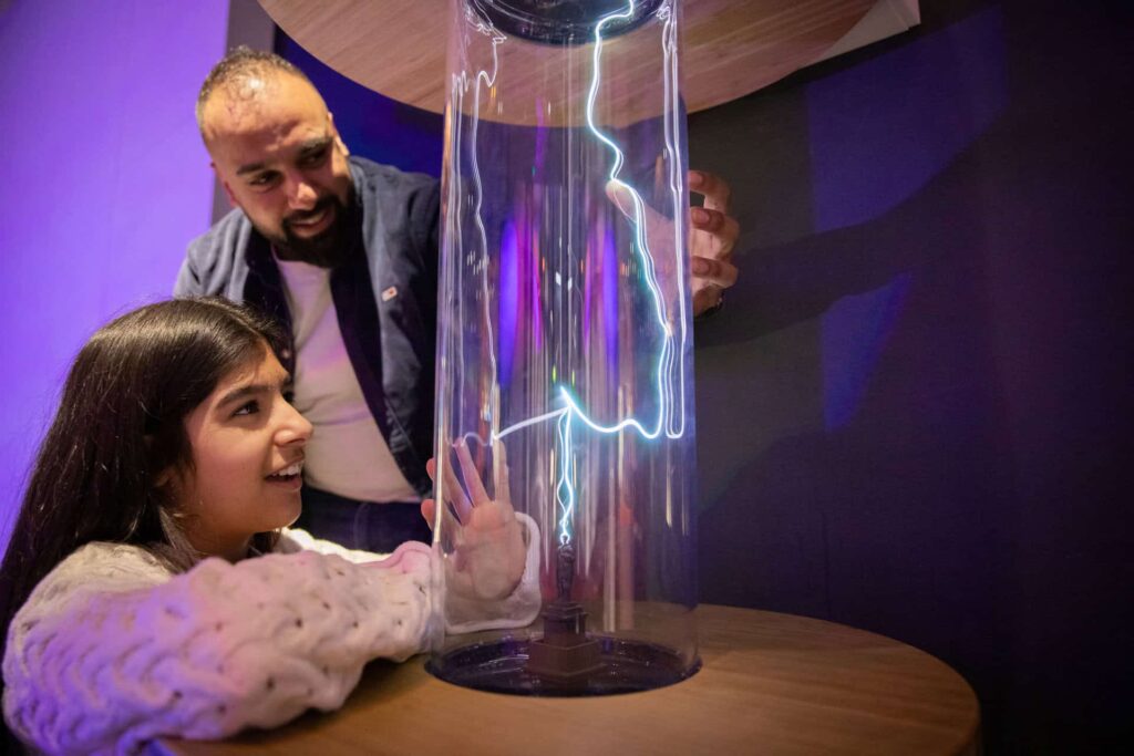 Father and daughter in Newcastle's Life Science Centre, enjoying hands-on exhibit demonstrating how lightning works.