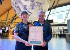 Z along with David in front of large replica of planet Earth, holding ASDC Award.