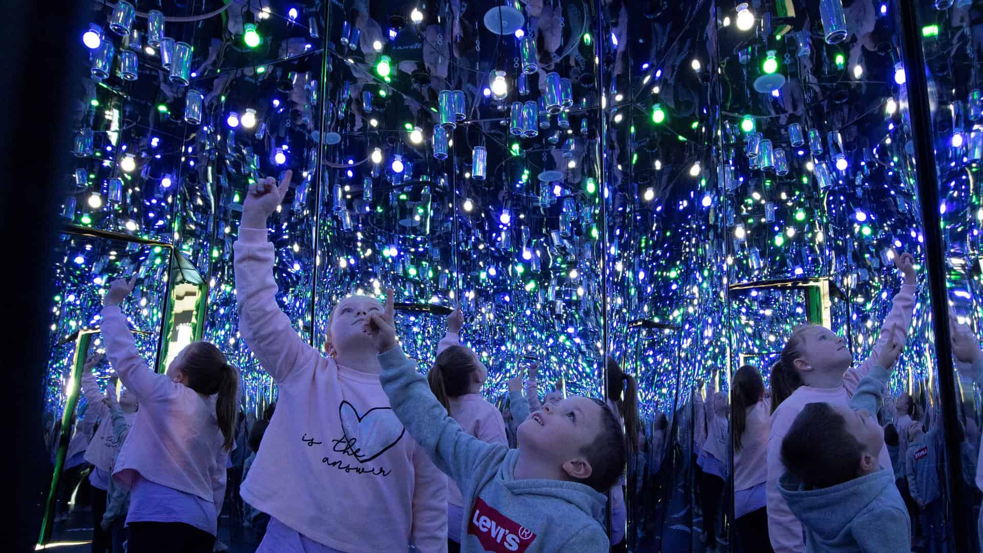 Young children looking up inside Infinity Room of recycled cans - a new exhibit at Life Science Centre in Newcastle.