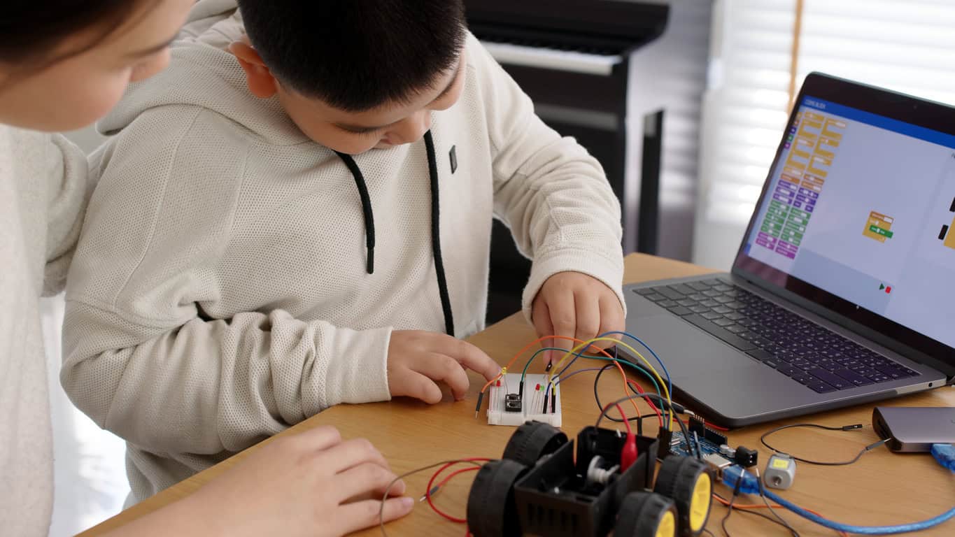 Young Asia Student Remotely Learn Online At Home With Parent In Coding Robot Car And Electronic Board Cable In STEM, STEAM, Mathematics Engineer Science Technology Computer Code In Robotics For Kids.