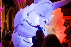 Person touching Luma - the giant, glowing robotic snail.