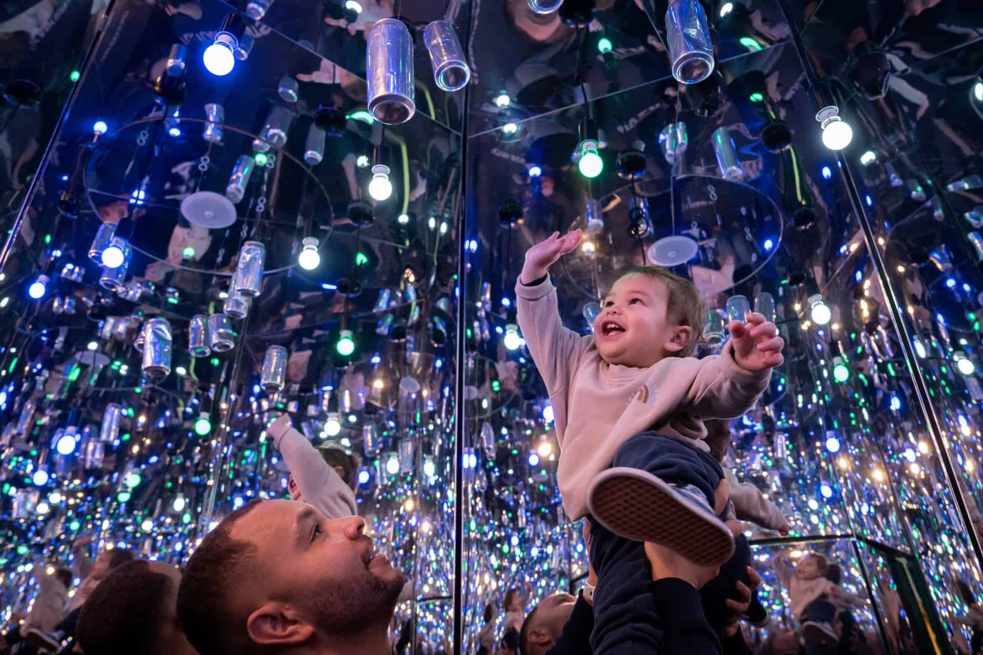 Father holding up child to can in Infinity Room, part of Life Science Centre in Newcastle.