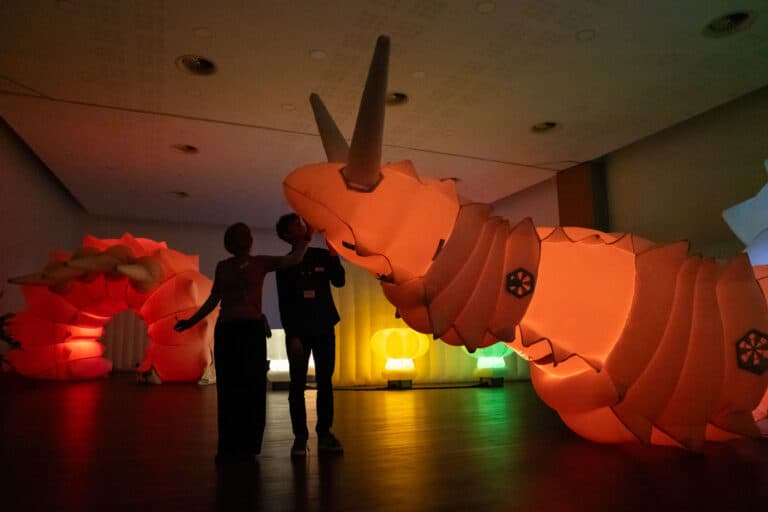 Adults stood in front of Luma - a giant, glowing robotic snail